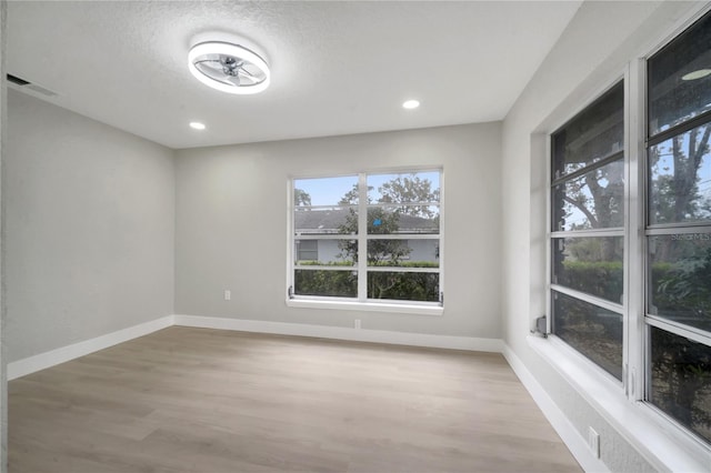 spare room with a textured ceiling and light hardwood / wood-style flooring