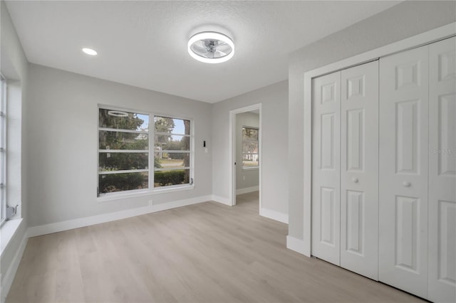 unfurnished bedroom with a closet, light hardwood / wood-style flooring, and a textured ceiling