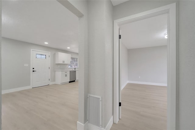 corridor with sink and light hardwood / wood-style flooring