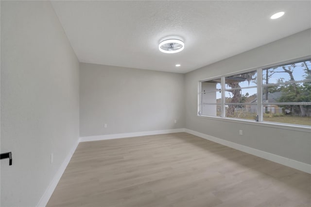 empty room with light hardwood / wood-style floors and a textured ceiling