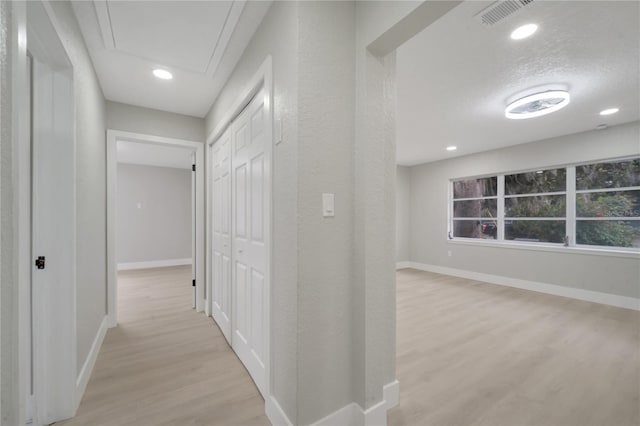 hallway featuring light wood-type flooring and a textured ceiling