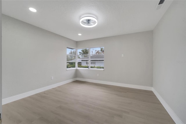 spare room with light hardwood / wood-style floors and a textured ceiling