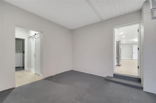 unfurnished room featuring concrete floors and a barn door