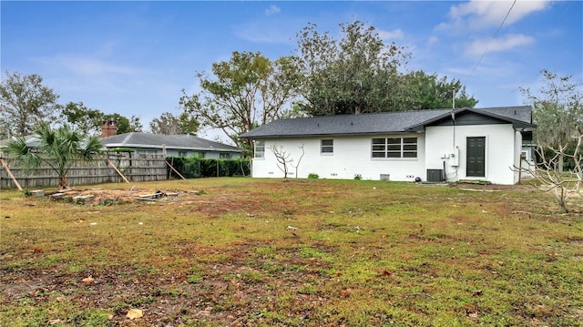 rear view of property with a lawn and cooling unit