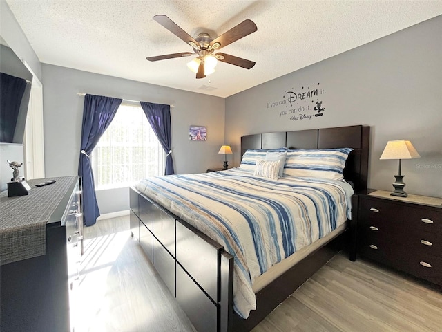 bedroom featuring ceiling fan, light hardwood / wood-style flooring, and a textured ceiling