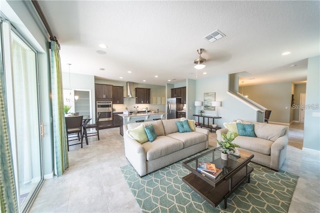 living room featuring ceiling fan and a textured ceiling