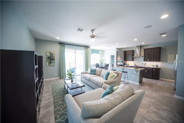 living room with a textured ceiling and ceiling fan