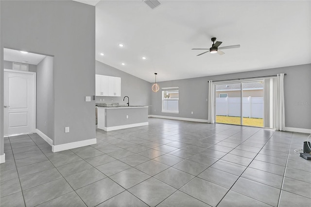 unfurnished living room with ceiling fan, sink, light tile patterned flooring, and vaulted ceiling