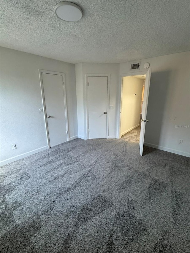 carpeted empty room with a textured ceiling