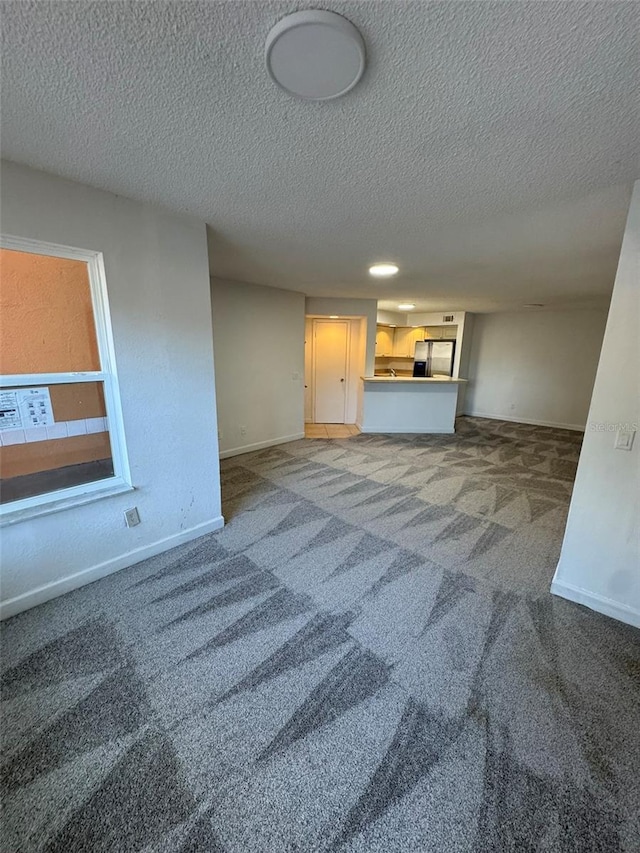 unfurnished living room with carpet flooring and a textured ceiling