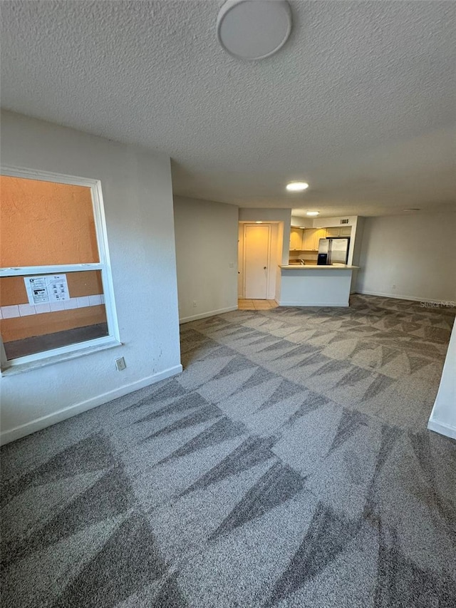 unfurnished living room with carpet flooring and a textured ceiling