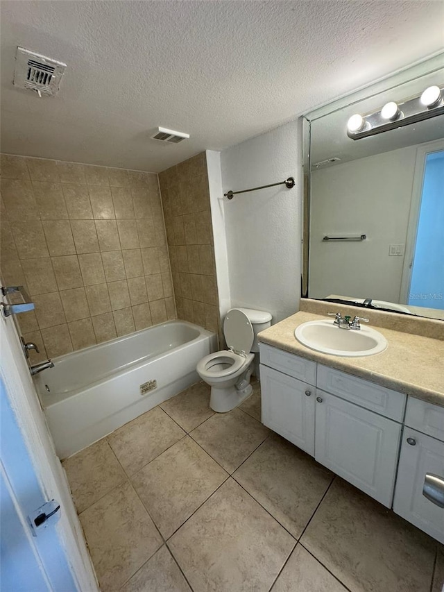 full bathroom featuring tile patterned floors, vanity, a textured ceiling, toilet, and tiled shower / bath