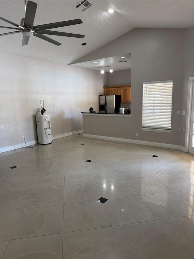 interior space featuring ceiling fan, electric water heater, high vaulted ceiling, a textured ceiling, and light tile patterned floors