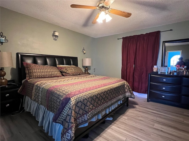 bedroom with ceiling fan, hardwood / wood-style floors, and a textured ceiling