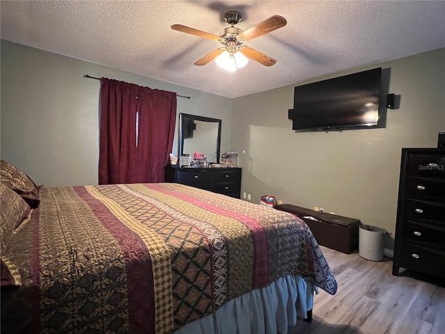 bedroom with ceiling fan, light hardwood / wood-style floors, and a textured ceiling