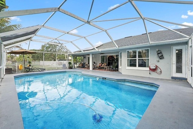 view of swimming pool with glass enclosure, ceiling fan, and a patio area