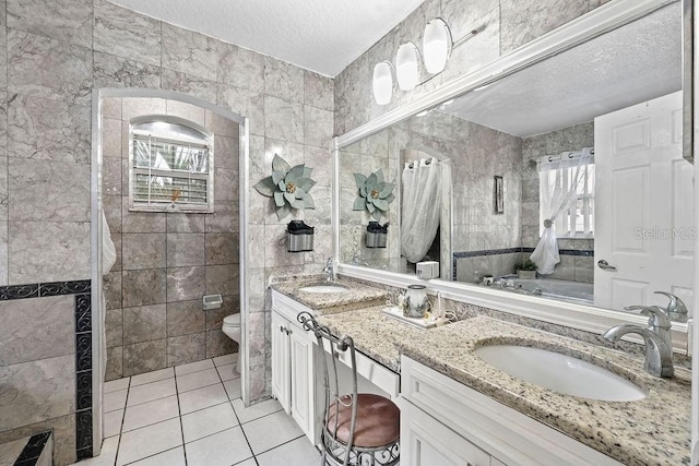 bathroom with a textured ceiling, tile patterned flooring, toilet, and tile walls