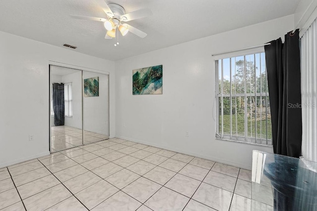 unfurnished bedroom with light tile patterned floors, a closet, and ceiling fan