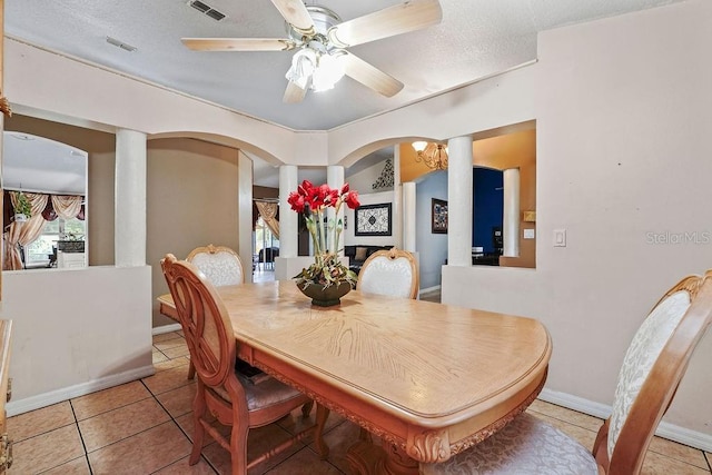 dining area featuring light tile patterned floors, visible vents, arched walkways, a ceiling fan, and a textured ceiling