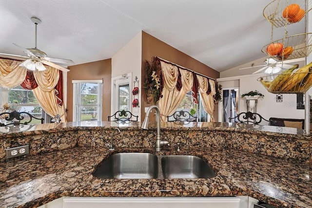 kitchen featuring white cabinets, a ceiling fan, vaulted ceiling, and a sink