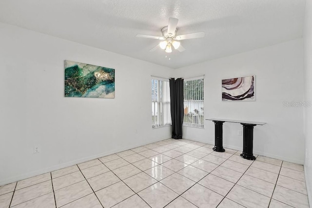 unfurnished room featuring a ceiling fan, a textured ceiling, baseboards, and light tile patterned floors