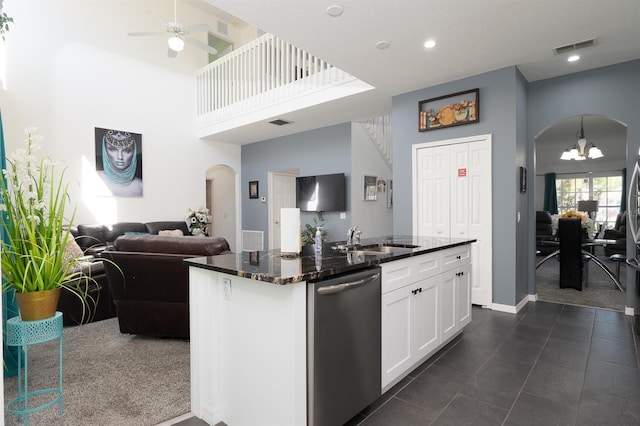 kitchen with dishwasher, sink, dark stone countertops, a center island with sink, and white cabinets