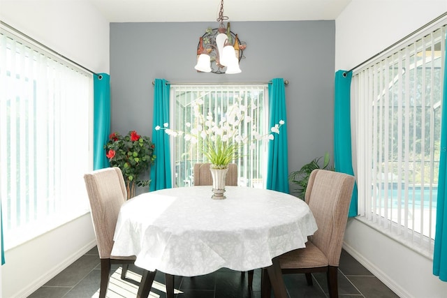 dining area with a notable chandelier, plenty of natural light, and dark tile patterned floors