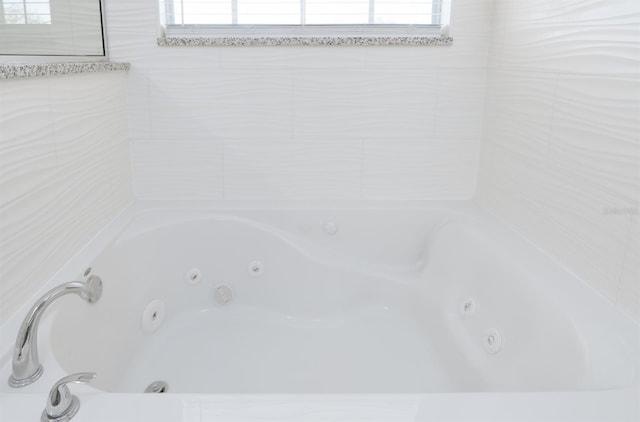 bathroom with a tub to relax in and a healthy amount of sunlight