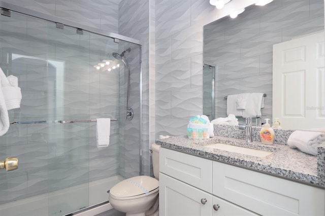 bathroom featuring an enclosed shower, vanity, toilet, and tile walls