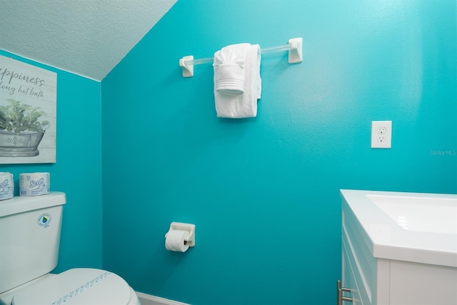 bathroom featuring vanity, toilet, lofted ceiling, and a textured ceiling