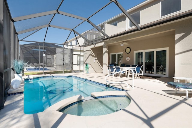 view of swimming pool featuring glass enclosure, ceiling fan, a patio, and an in ground hot tub