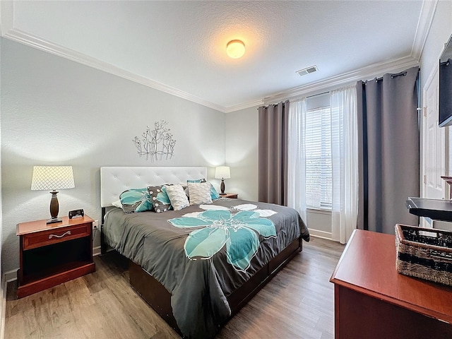 bedroom with hardwood / wood-style flooring, crown molding, and a textured ceiling