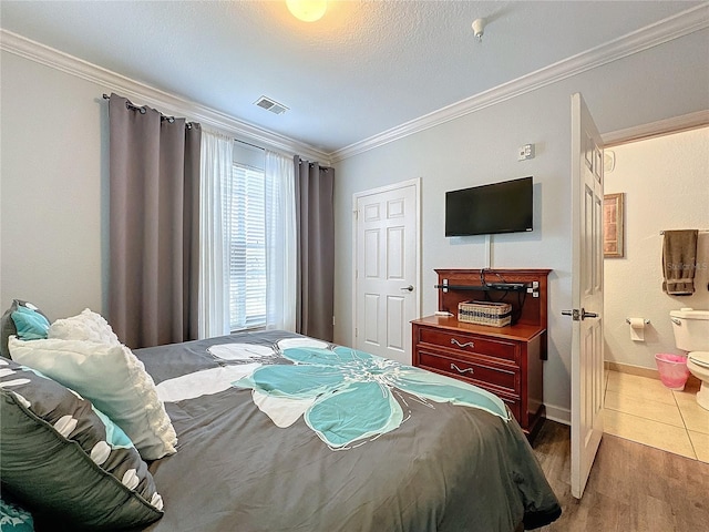 bedroom featuring ensuite bath, crown molding, a textured ceiling, and hardwood / wood-style flooring