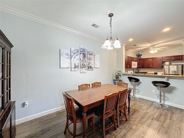 dining area featuring crown molding, light hardwood / wood-style floors, and ceiling fan with notable chandelier