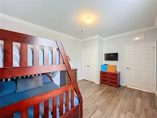 bedroom featuring a textured ceiling, light hardwood / wood-style floors, and crown molding