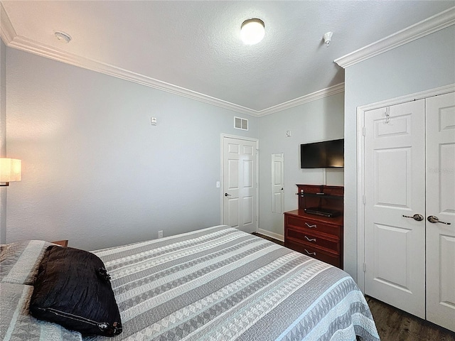 bedroom with a textured ceiling, a closet, dark hardwood / wood-style floors, and ornamental molding