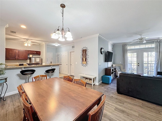 dining area with crown molding, french doors, ceiling fan with notable chandelier, and light hardwood / wood-style flooring