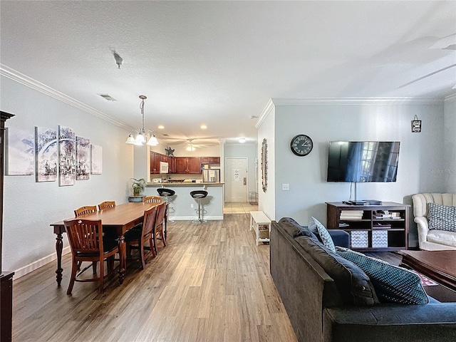 living room with a chandelier, a textured ceiling, light hardwood / wood-style floors, and crown molding