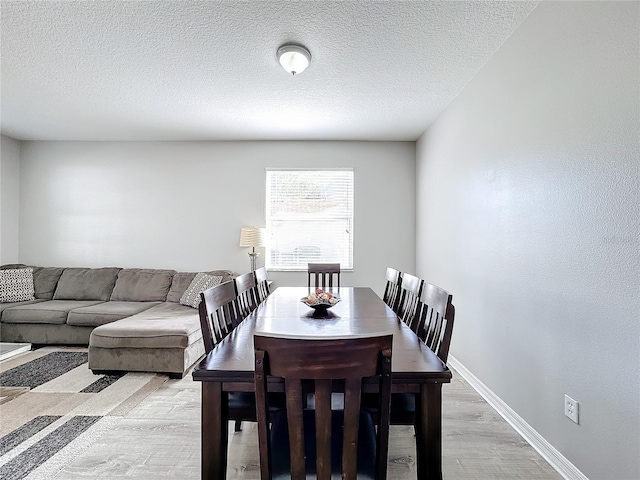 dining room with light hardwood / wood-style flooring and a textured ceiling