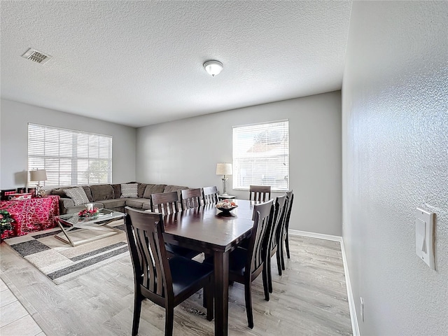 dining room with light hardwood / wood-style floors and a textured ceiling