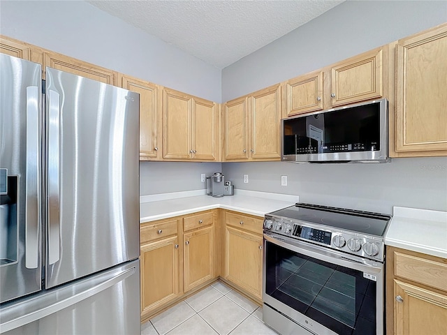 kitchen featuring light brown cabinets, light tile patterned floors, stainless steel appliances, and a textured ceiling