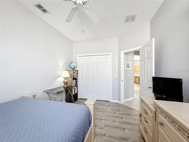 bedroom featuring a textured ceiling, a closet, light hardwood / wood-style flooring, and ceiling fan