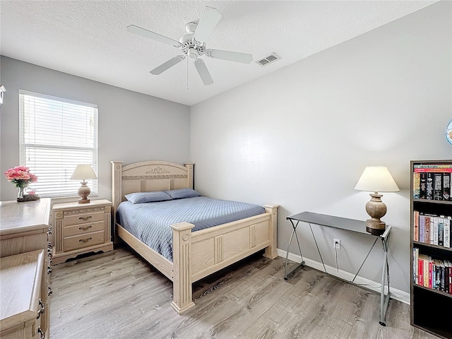 bedroom with a textured ceiling, light hardwood / wood-style floors, and ceiling fan