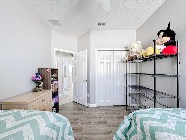 bedroom featuring ceiling fan, light hardwood / wood-style floors, a textured ceiling, and a closet