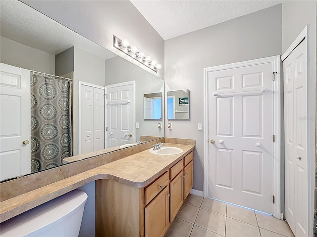 bathroom featuring tile patterned flooring, vanity, toilet, and a textured ceiling