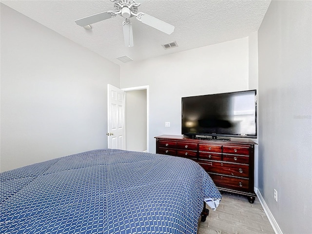 bedroom with ceiling fan, light hardwood / wood-style flooring, and a textured ceiling