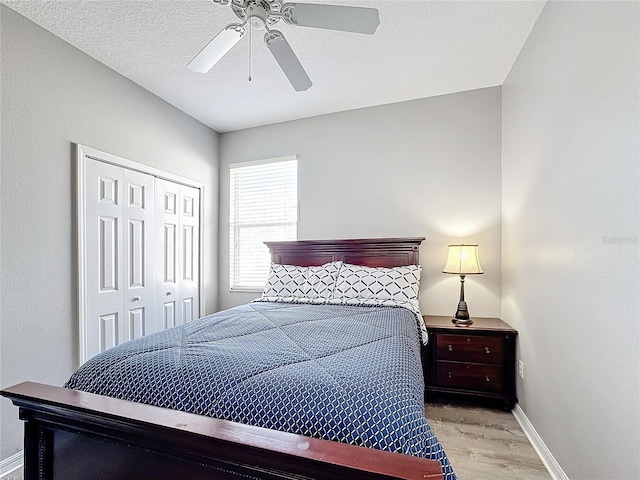 bedroom featuring a textured ceiling, light wood-type flooring, a closet, and ceiling fan