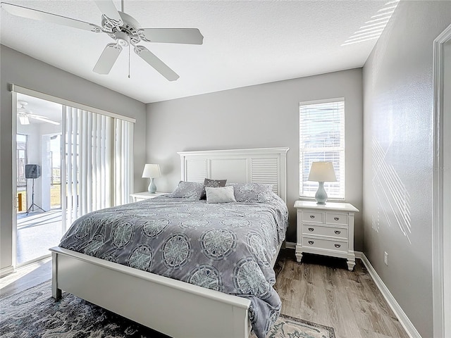 bedroom featuring access to exterior, a textured ceiling, light wood-type flooring, and ceiling fan