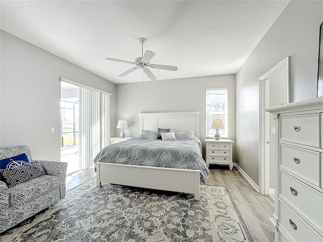 bedroom featuring ceiling fan, light hardwood / wood-style floors, a textured ceiling, and access to outside