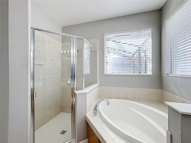 bathroom with plus walk in shower and a textured ceiling